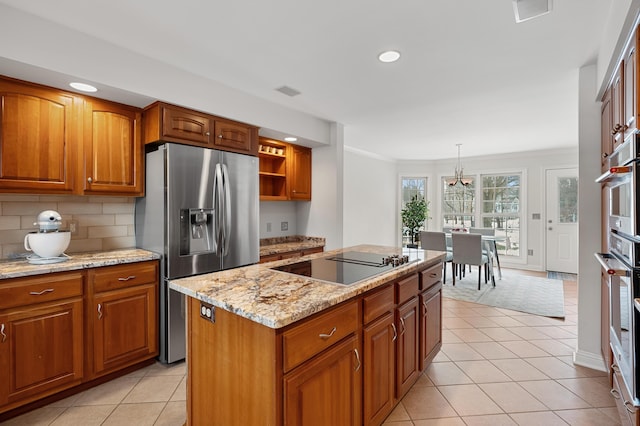 kitchen with pendant lighting, light tile patterned floors, appliances with stainless steel finishes, brown cabinetry, and a kitchen island