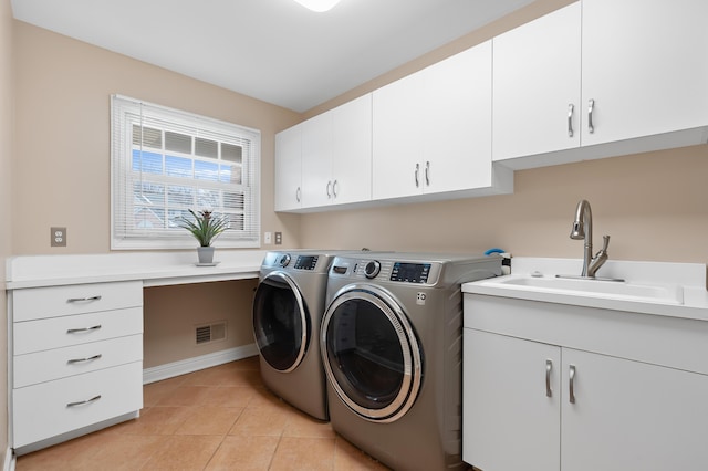 laundry room featuring cabinet space, light tile patterned floors, visible vents, washer and clothes dryer, and a sink