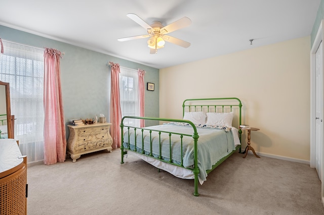 bedroom featuring light carpet, a ceiling fan, and baseboards