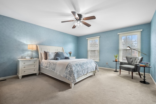 bedroom with light carpet, ceiling fan, visible vents, and baseboards