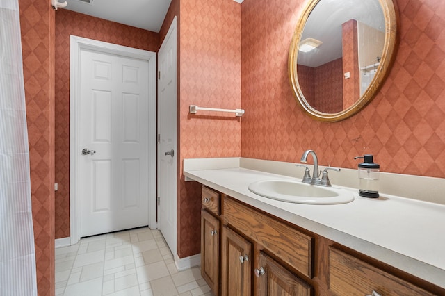 bathroom featuring vanity, baseboards, and wallpapered walls