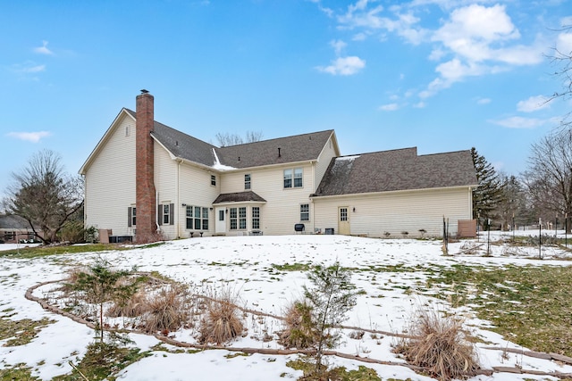snow covered back of property featuring a chimney