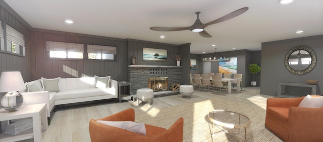 living room with a brick fireplace, ceiling fan with notable chandelier, wood walls, and light hardwood / wood-style flooring