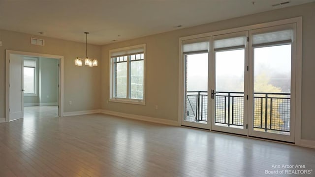 unfurnished room with light wood-type flooring and an inviting chandelier