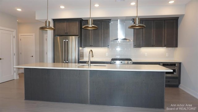 kitchen with pendant lighting, wall chimney range hood, and appliances with stainless steel finishes