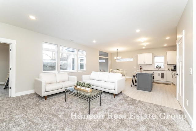 carpeted living room featuring a notable chandelier and sink