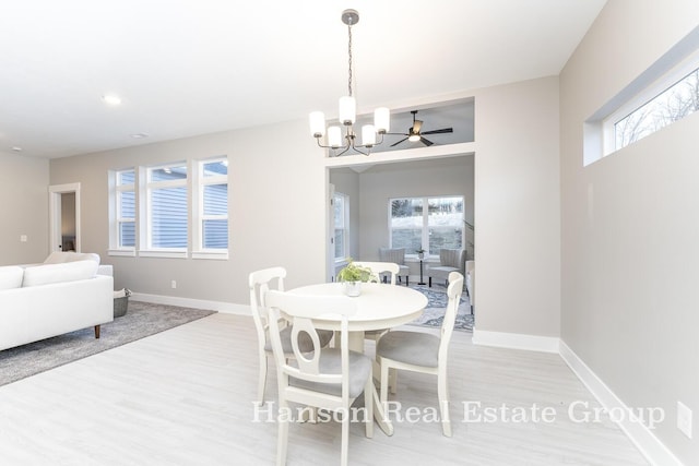 dining area featuring a healthy amount of sunlight, ceiling fan with notable chandelier, and light wood-type flooring