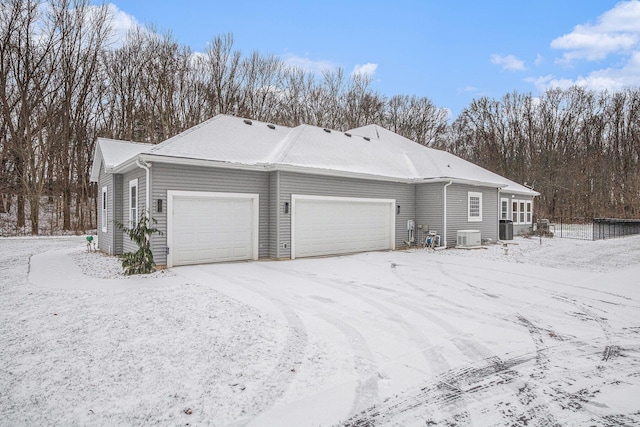 view of snow covered exterior with a garage and central AC