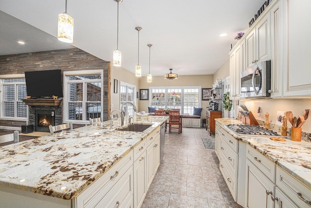 kitchen featuring appliances with stainless steel finishes, light stone counters, a spacious island, sink, and pendant lighting