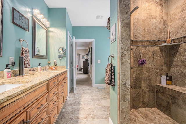 bathroom featuring tiled shower and vanity