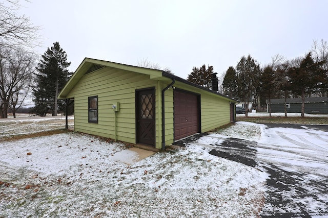 snow covered structure featuring a garage