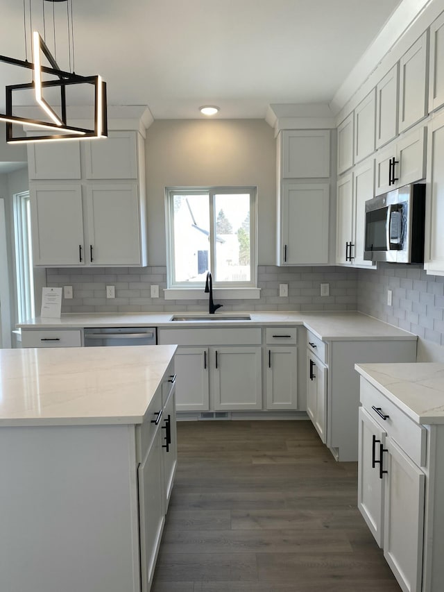 kitchen with white cabinetry, sink, decorative light fixtures, and appliances with stainless steel finishes