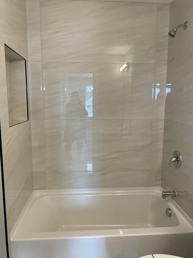 bathroom featuring tiled shower / bath combo and toilet