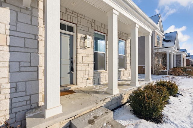 snow covered property entrance featuring covered porch