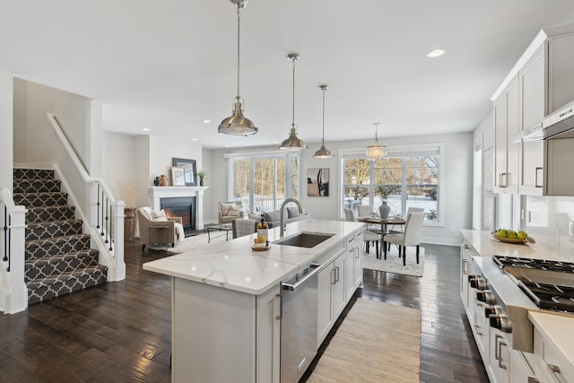 kitchen featuring a kitchen island with sink, pendant lighting, stainless steel dishwasher, and white cabinetry