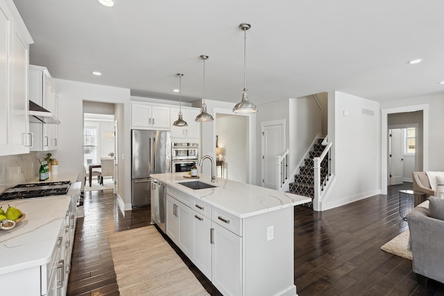 kitchen with stainless steel appliances, sink, a center island with sink, and white cabinets