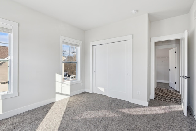 unfurnished bedroom featuring multiple windows, carpet flooring, and a closet