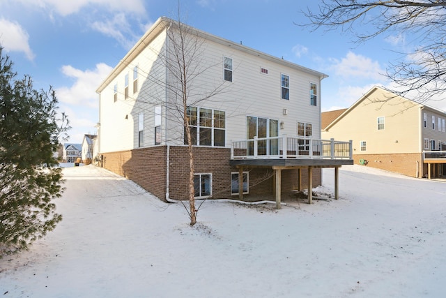 snow covered back of property with a wooden deck