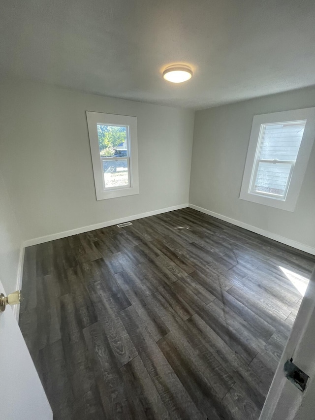 unfurnished room with dark hardwood / wood-style flooring