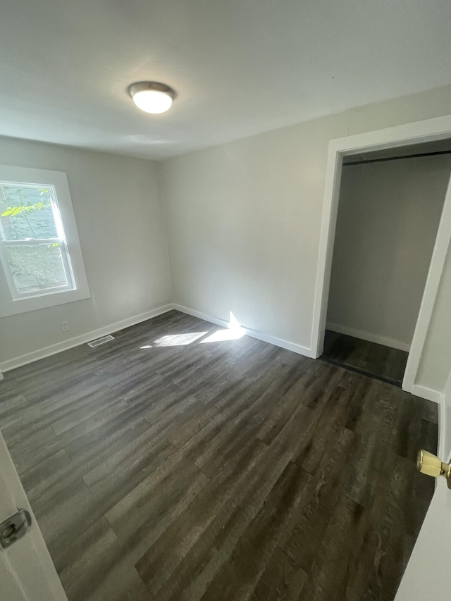 unfurnished bedroom with dark hardwood / wood-style flooring and a closet