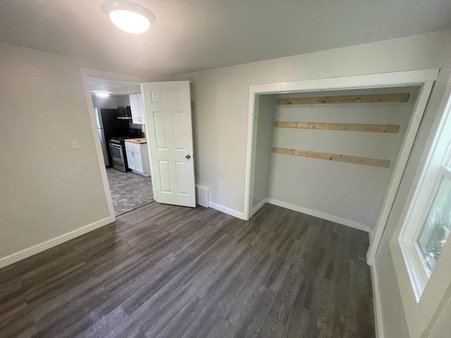 unfurnished bedroom with dark hardwood / wood-style floors, stainless steel fridge, and a closet