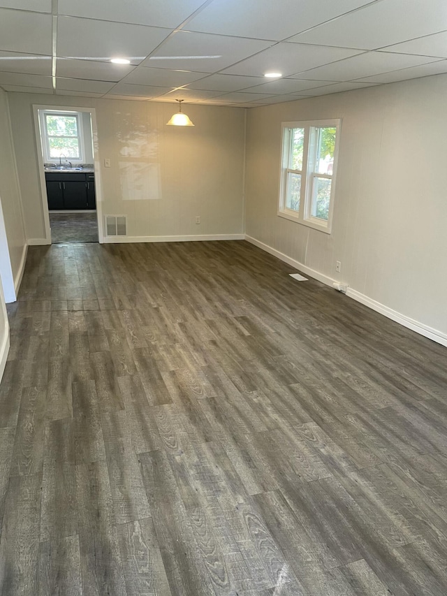 empty room with a paneled ceiling, dark wood-type flooring, and sink