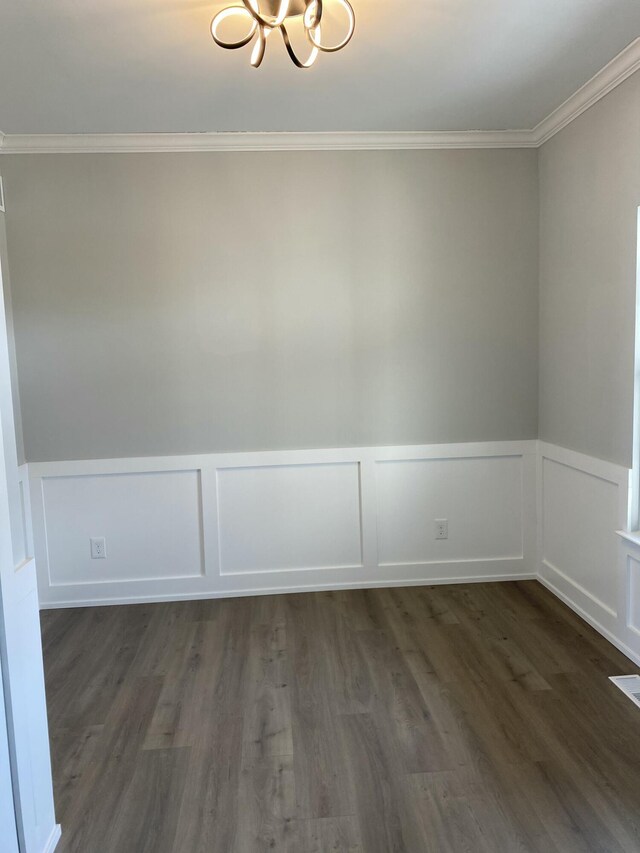 unfurnished room featuring a notable chandelier, dark hardwood / wood-style floors, and ornamental molding