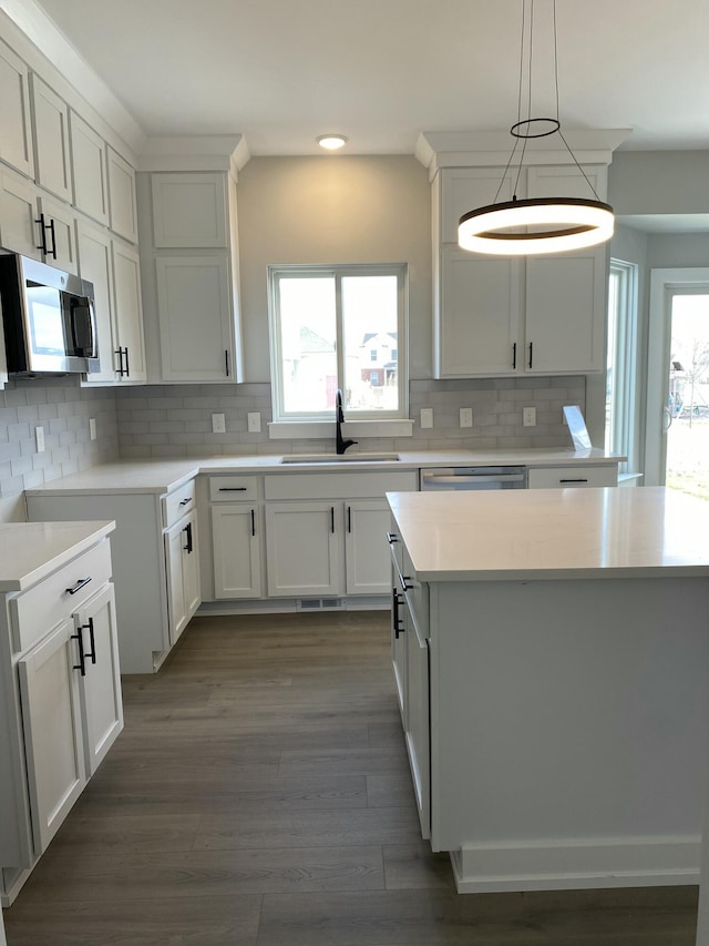 kitchen with pendant lighting, sink, appliances with stainless steel finishes, tasteful backsplash, and white cabinetry