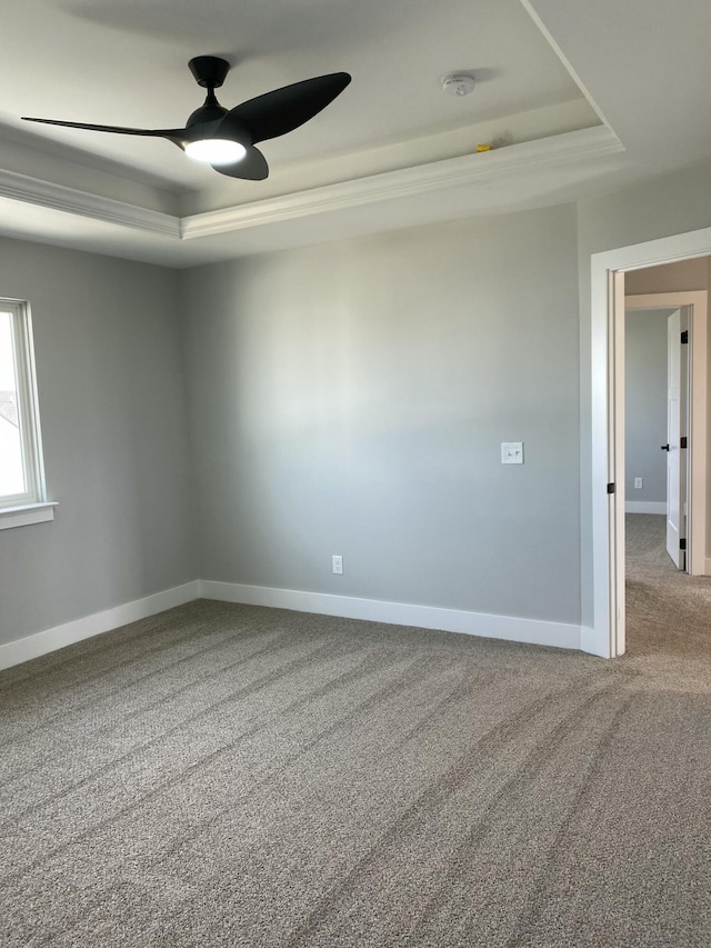 spare room featuring carpet, ceiling fan, and a raised ceiling