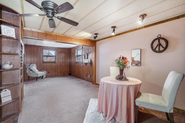 interior space with carpet floors, ceiling fan, and wood walls