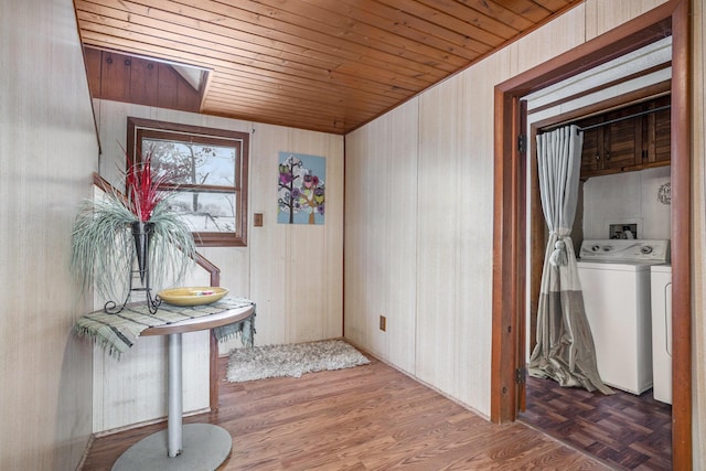 entrance foyer featuring wood walls, wood-type flooring, wooden ceiling, and washing machine and clothes dryer