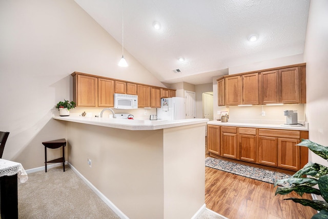 kitchen featuring white appliances, light wood-type flooring, a textured ceiling, decorative light fixtures, and kitchen peninsula