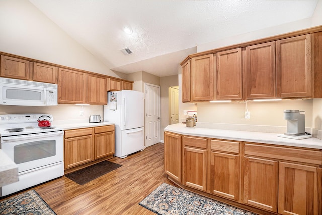 kitchen featuring a textured ceiling, lofted ceiling, white appliances, and light wood-type flooring