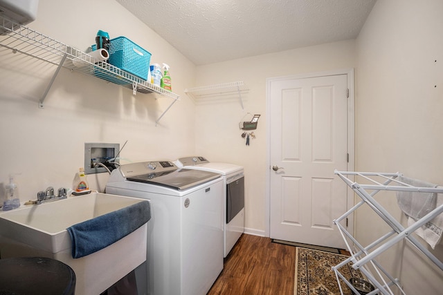 clothes washing area featuring washer and dryer, a textured ceiling, dark hardwood / wood-style floors, and sink