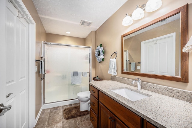 bathroom with vanity, a textured ceiling, toilet, and walk in shower