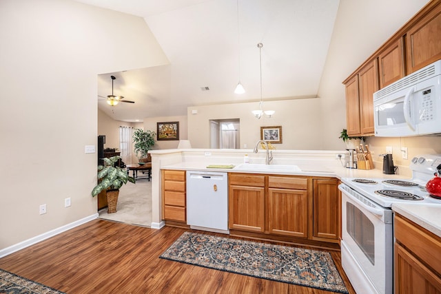 kitchen featuring kitchen peninsula, ceiling fan with notable chandelier, white appliances, sink, and decorative light fixtures