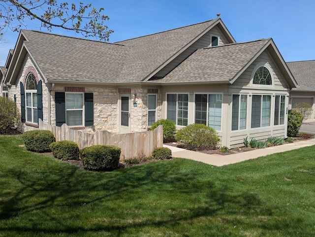 view of front of property featuring fence, roof with shingles, and a front lawn