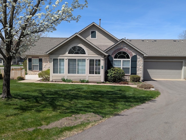 ranch-style home featuring roof with shingles, stone siding, a garage, and aphalt driveway