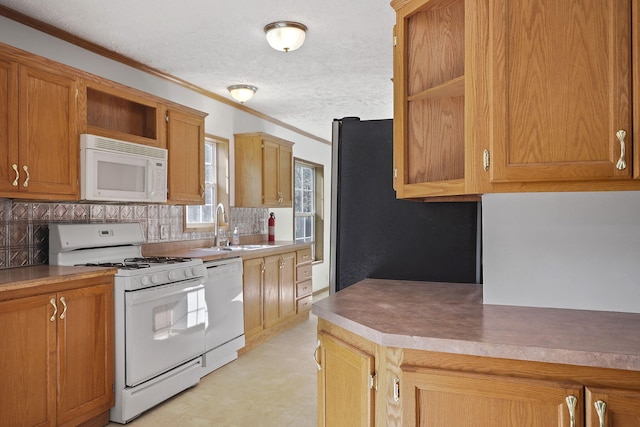 kitchen with sink, white appliances, a textured ceiling, and ornamental molding