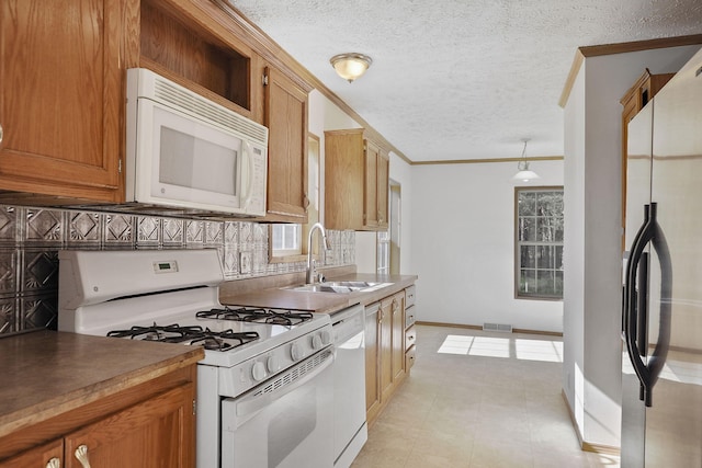 kitchen with sink, a textured ceiling, decorative light fixtures, white appliances, and decorative backsplash