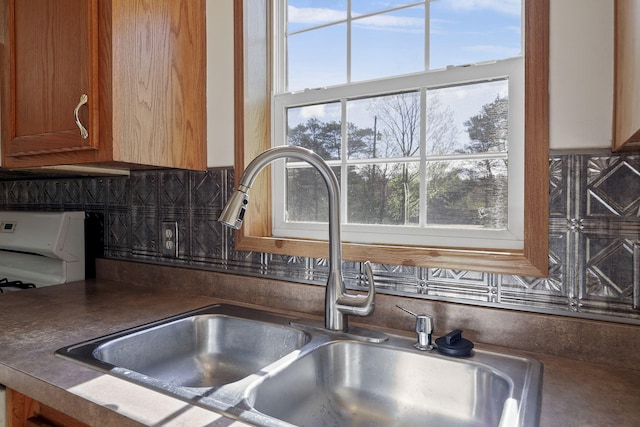 interior details featuring backsplash, white stove, and sink