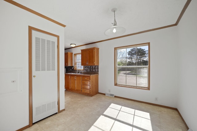 kitchen with crown molding, sink, light tile patterned floors, tasteful backsplash, and decorative light fixtures