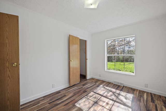 spare room with a textured ceiling and dark wood-type flooring