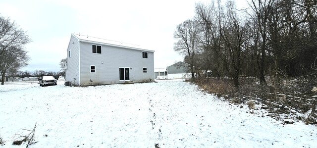 snow covered rear of property featuring central AC