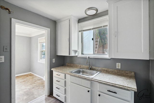 kitchen with white cabinetry, sink, a healthy amount of sunlight, and light hardwood / wood-style flooring