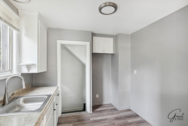 kitchen featuring white cabinets, light hardwood / wood-style flooring, and sink