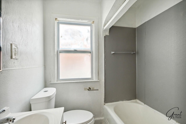 bathroom with toilet, sink, and a tub