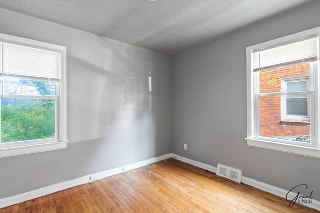 empty room with light hardwood / wood-style floors and a textured ceiling