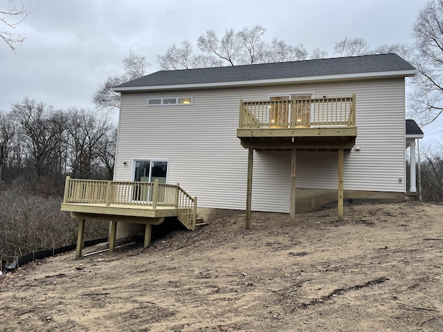 rear view of property with a shingled roof and a deck