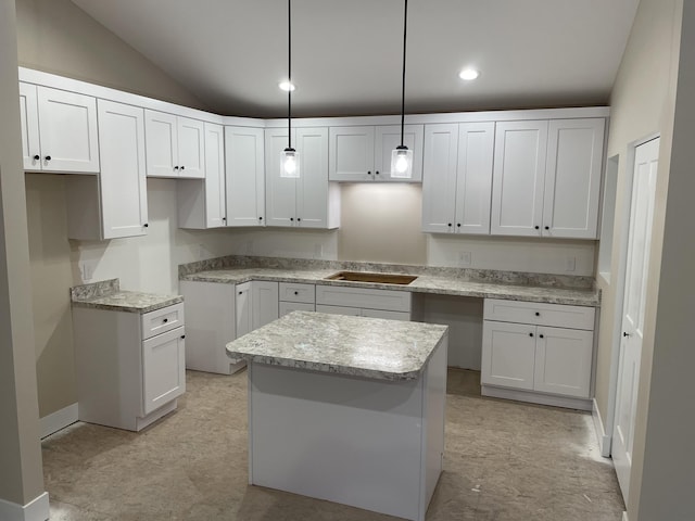 kitchen featuring lofted ceiling, decorative light fixtures, a center island, and white cabinets